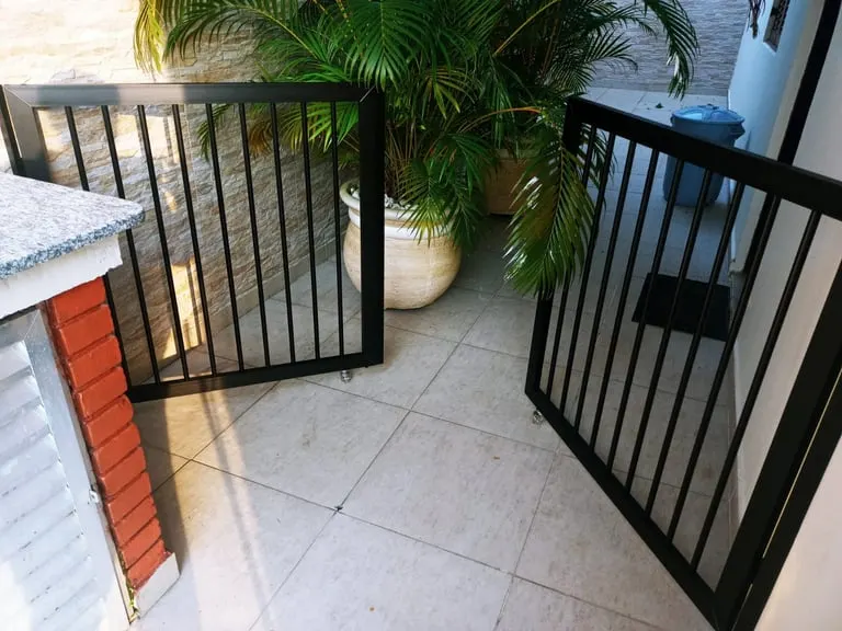 Portão de alumínio preto instalado em fachada residencial moderna.